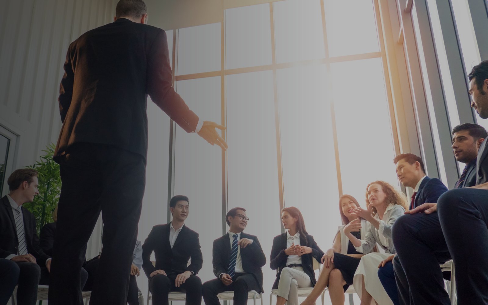 A facilitator leading a seated cohort of business professionals in a bright, modern workspace